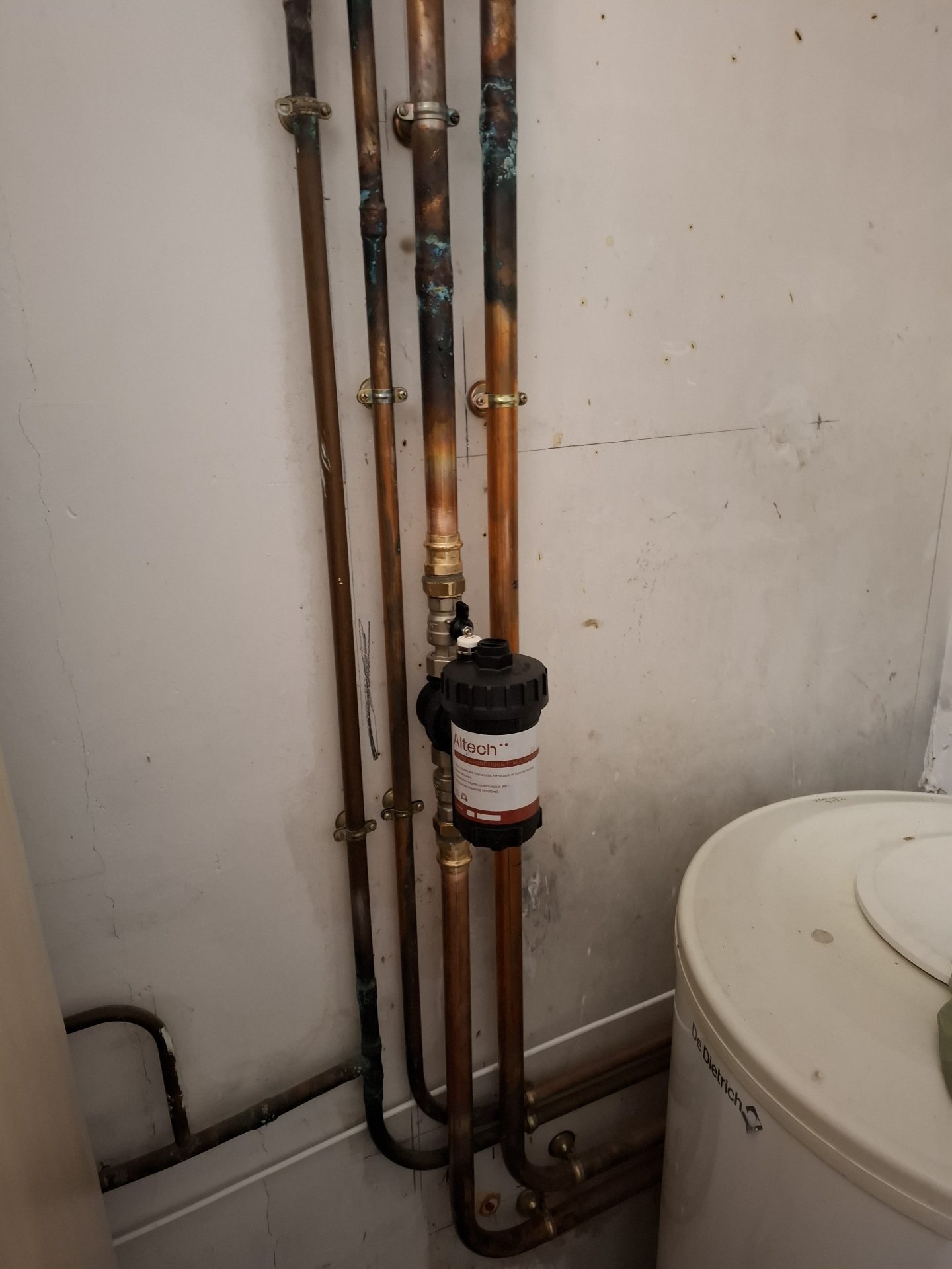 Installation d'un chauffe-eau Atlantic et de ses raccords de sécurité dans un garage, réalisée avec soin par Jimmy Paul, votre plombier à Billère.