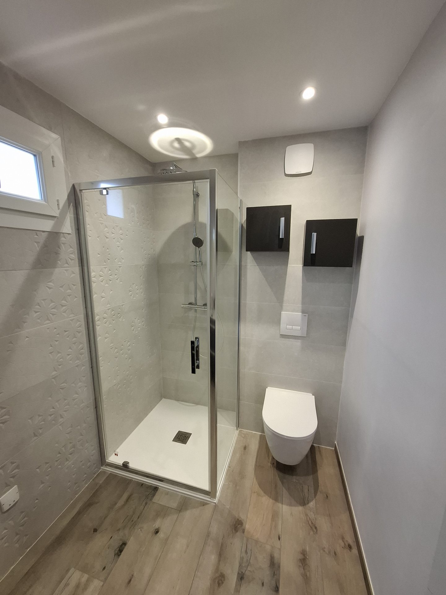 Aménagement complet d'un ensemble douche et WC avec meuble de rangement noir, étape clé d'une rénovation de salle de bain par l'artisan Jimmy Paul à Lons.