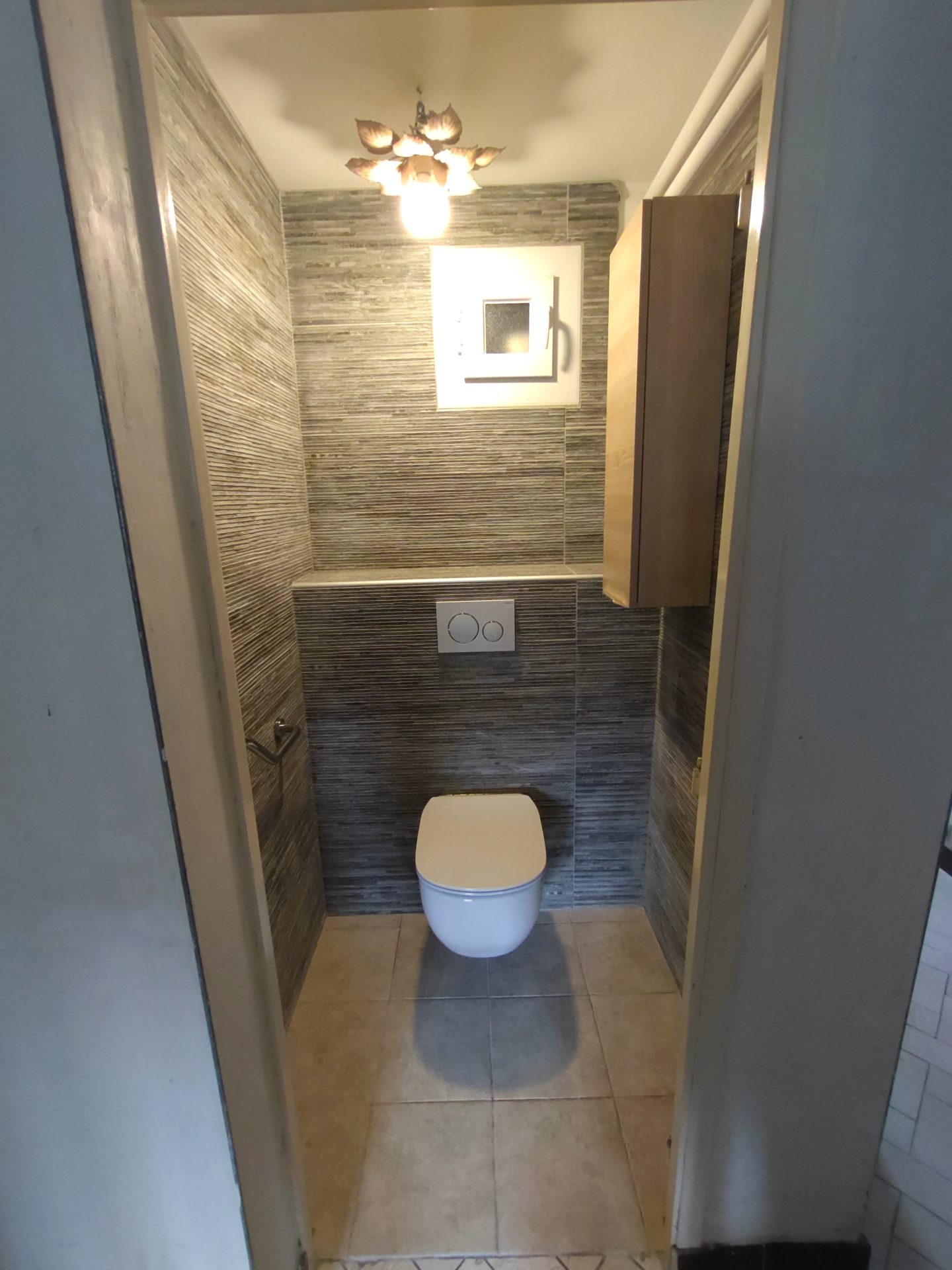 Installation d'un WC suspendu avec chasse d'eau murale intégrée et carrelage moderne gris, fruit d'une rénovation de salle de bain par Jimmy Paul sur Jurançon.