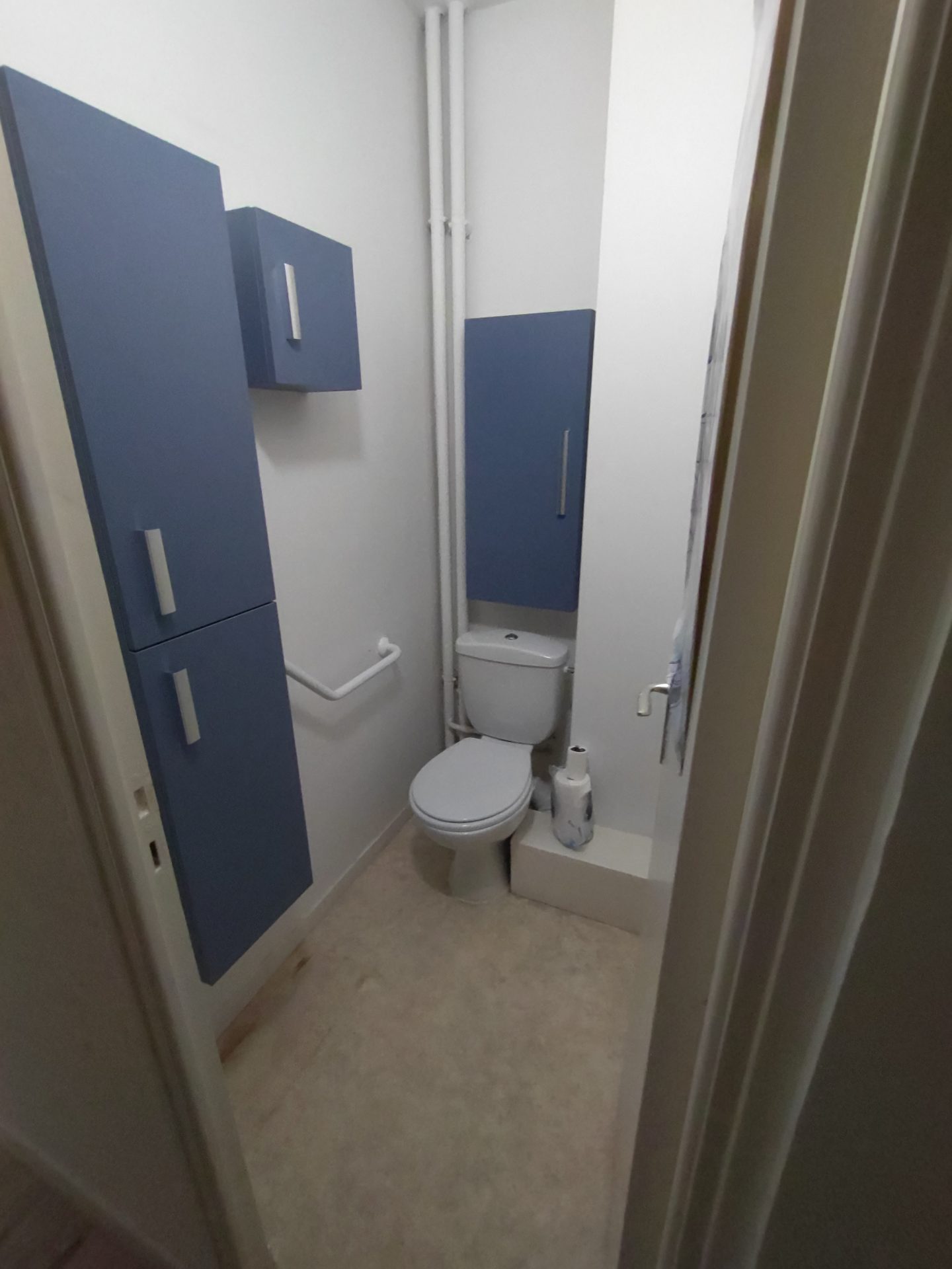 Agencement astucieux avec WC classique et meubles bleus pour optimiser une petite pièce, lors d'une rénovation de salle de bain menée par Jimmy Paul à Gelos.
