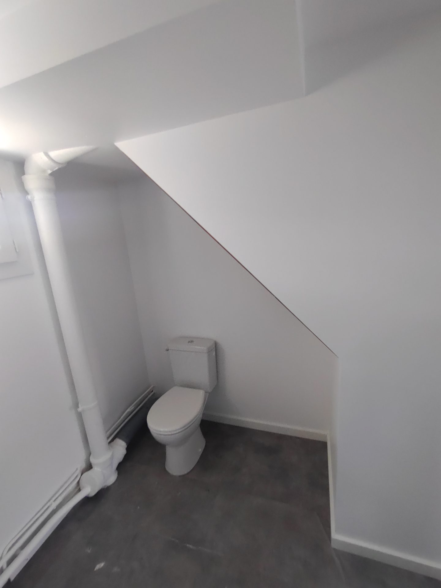Intégration astucieuse d'un WC classique sous un escalier, une solution d'optimisation lors d'une rénovation de salle de bain par Jimmy Paul à Morlaàs.
