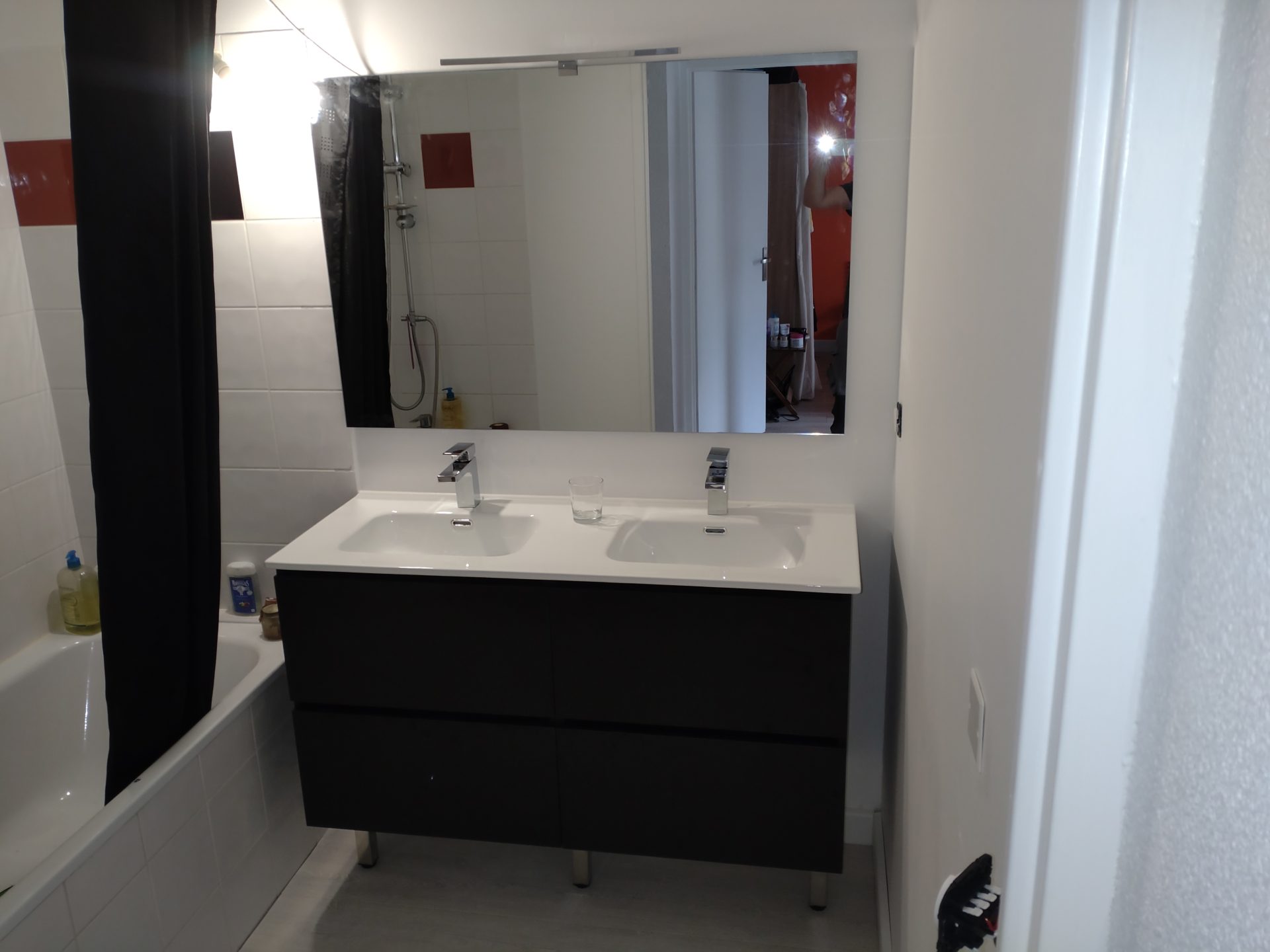 Aménagement élégant avec baignoire, grand miroir et double vasque sur meuble noir sur pied, par Jimmy Paul, expert en rénovation de salle de bain à Jurançon.